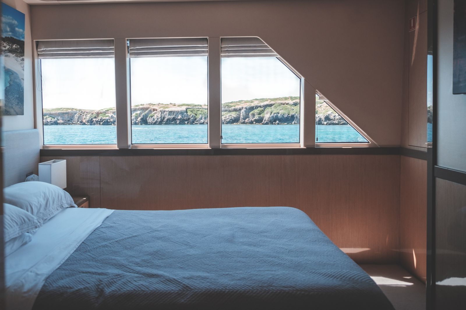 Bed facing a wall of wide windows onto the water, the view that sells river cruise suites