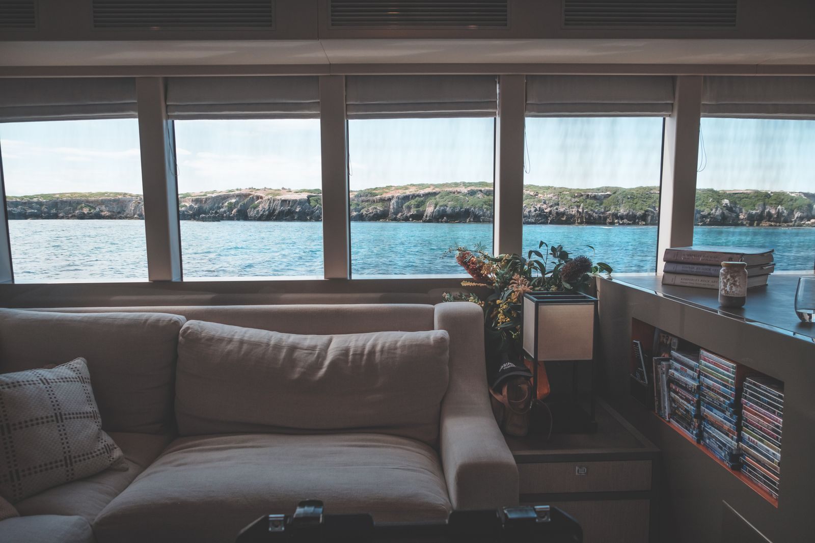 Sitting room with a sofa beside a row of wide windows over the water